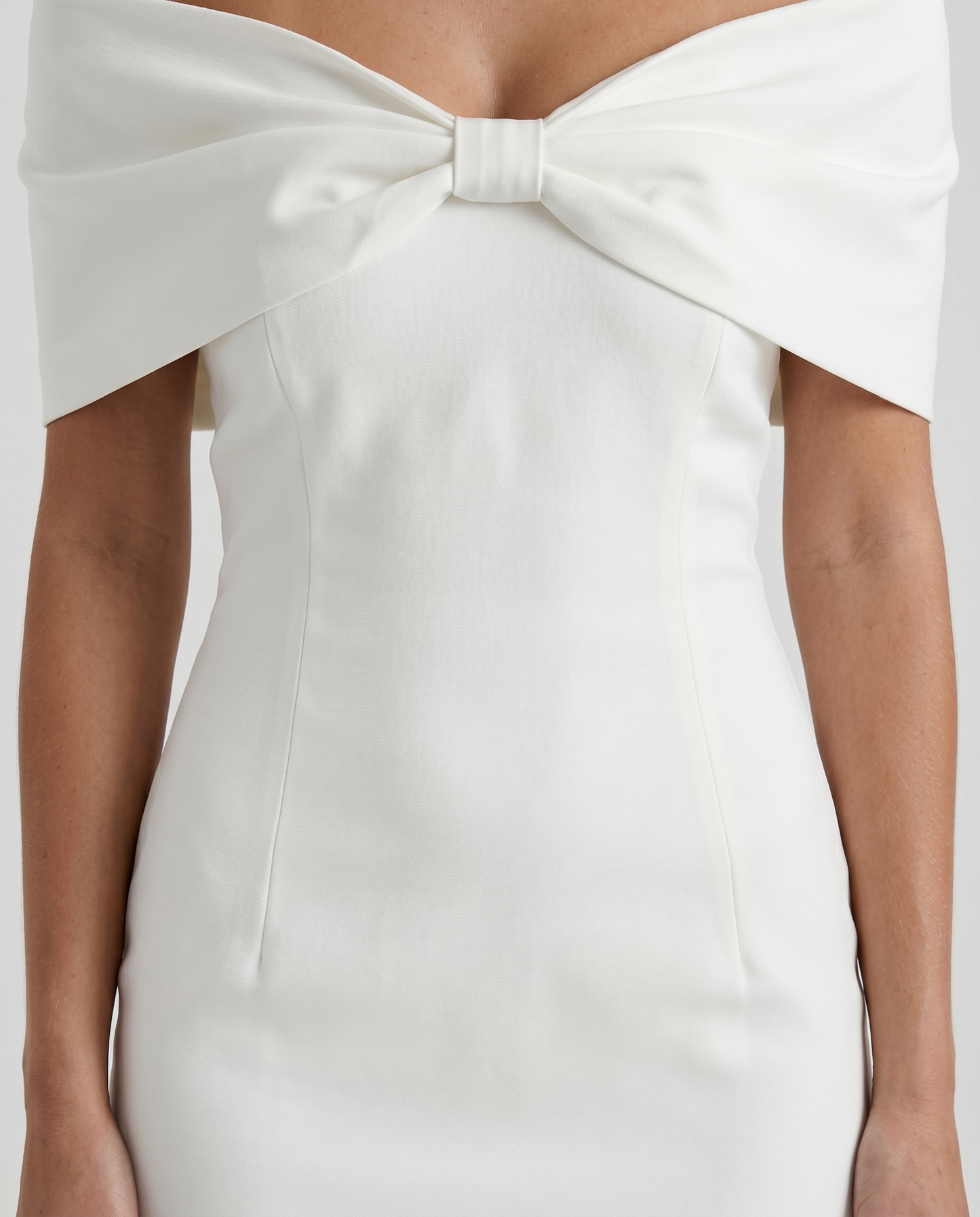 Women white mini dress closeup of off shoulder neckline, center bust bow, and cap sleeves