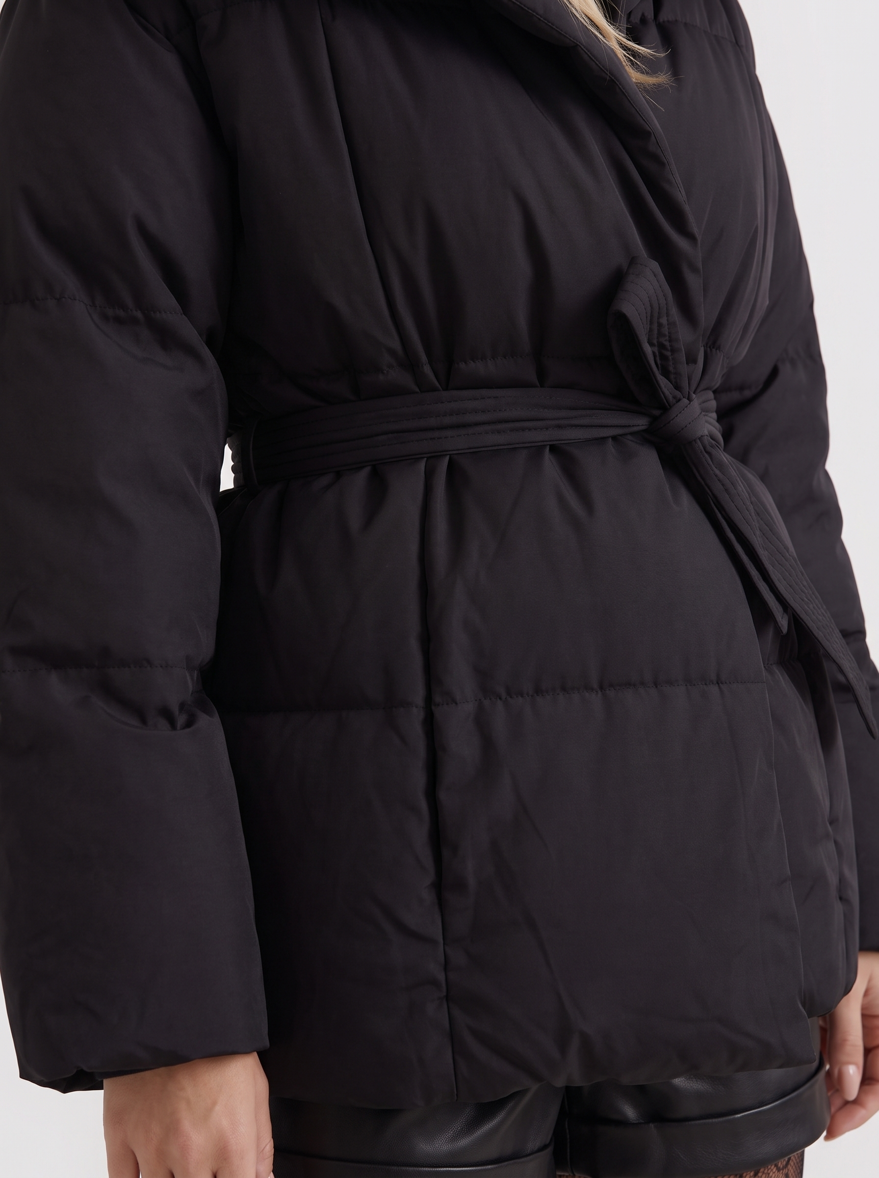 Women black oversized padded jacket with wide portrait collar and tie waist belt, fabric closeup