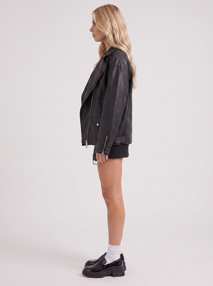 Women black oversized faux leather biker jacket with asymmetric zip and studded belt, side view