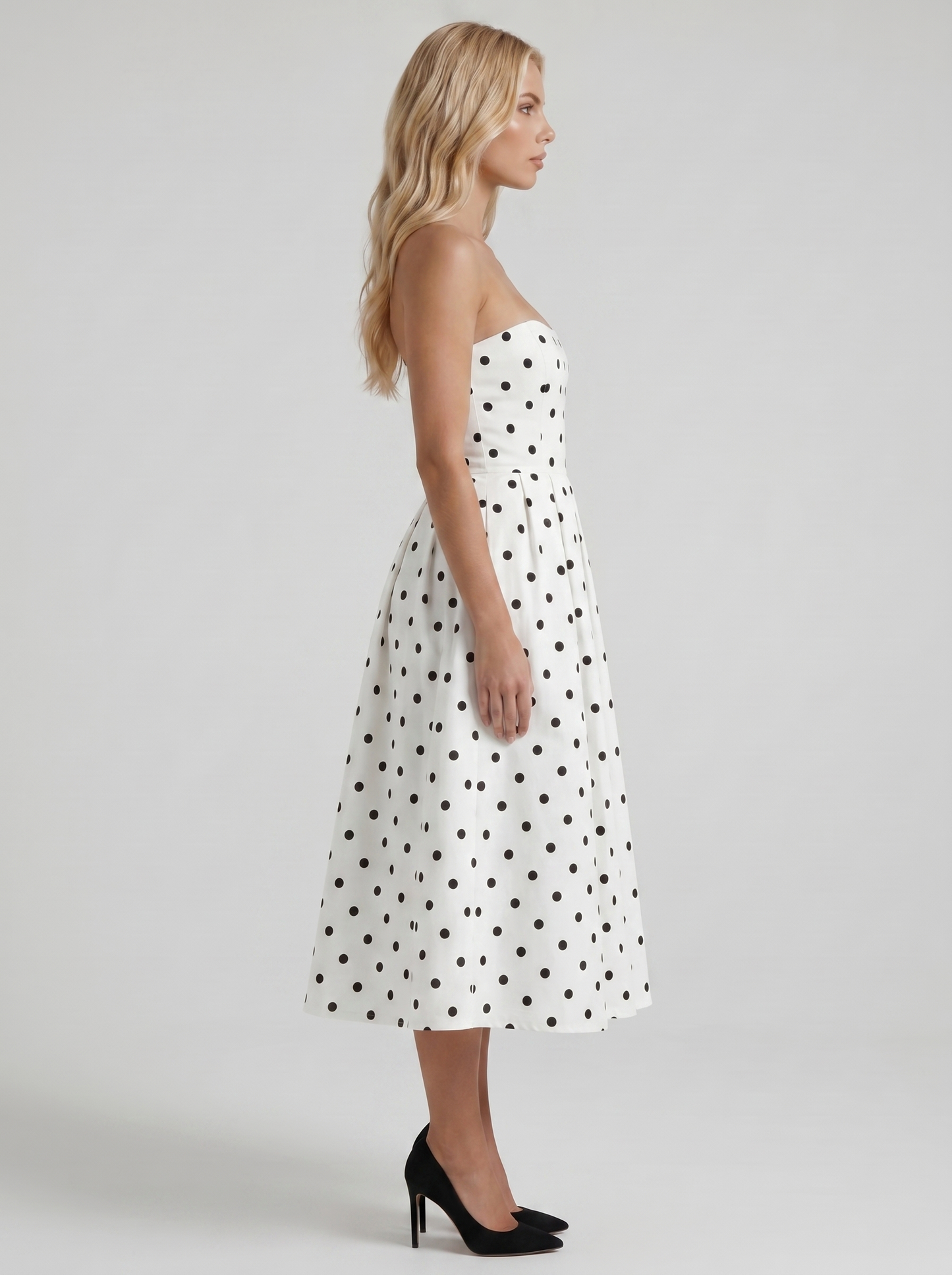 Women black polka dot strapless pleated midi dress with fitted bodice, side profile
