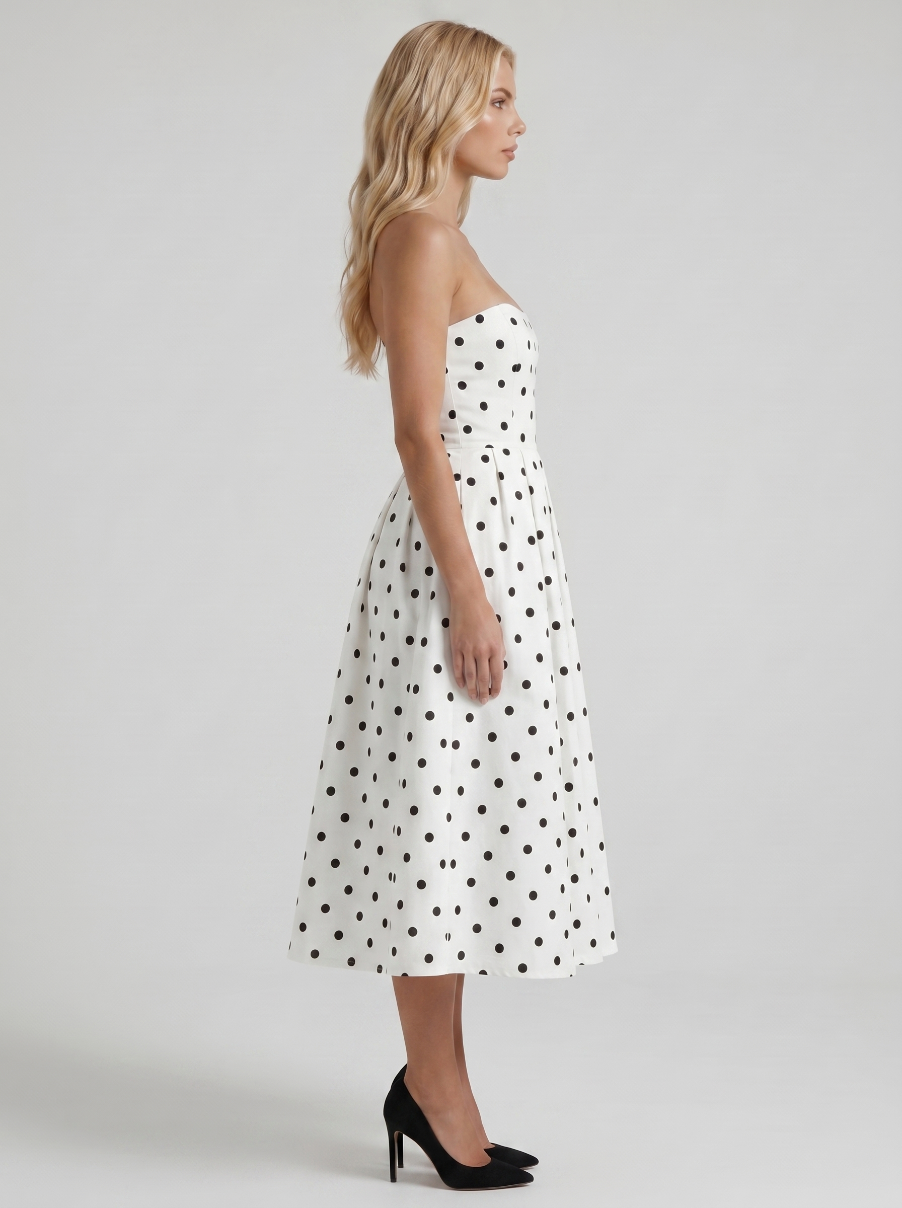 Women black polka dot strapless pleated midi dress with fitted bodice, side profile