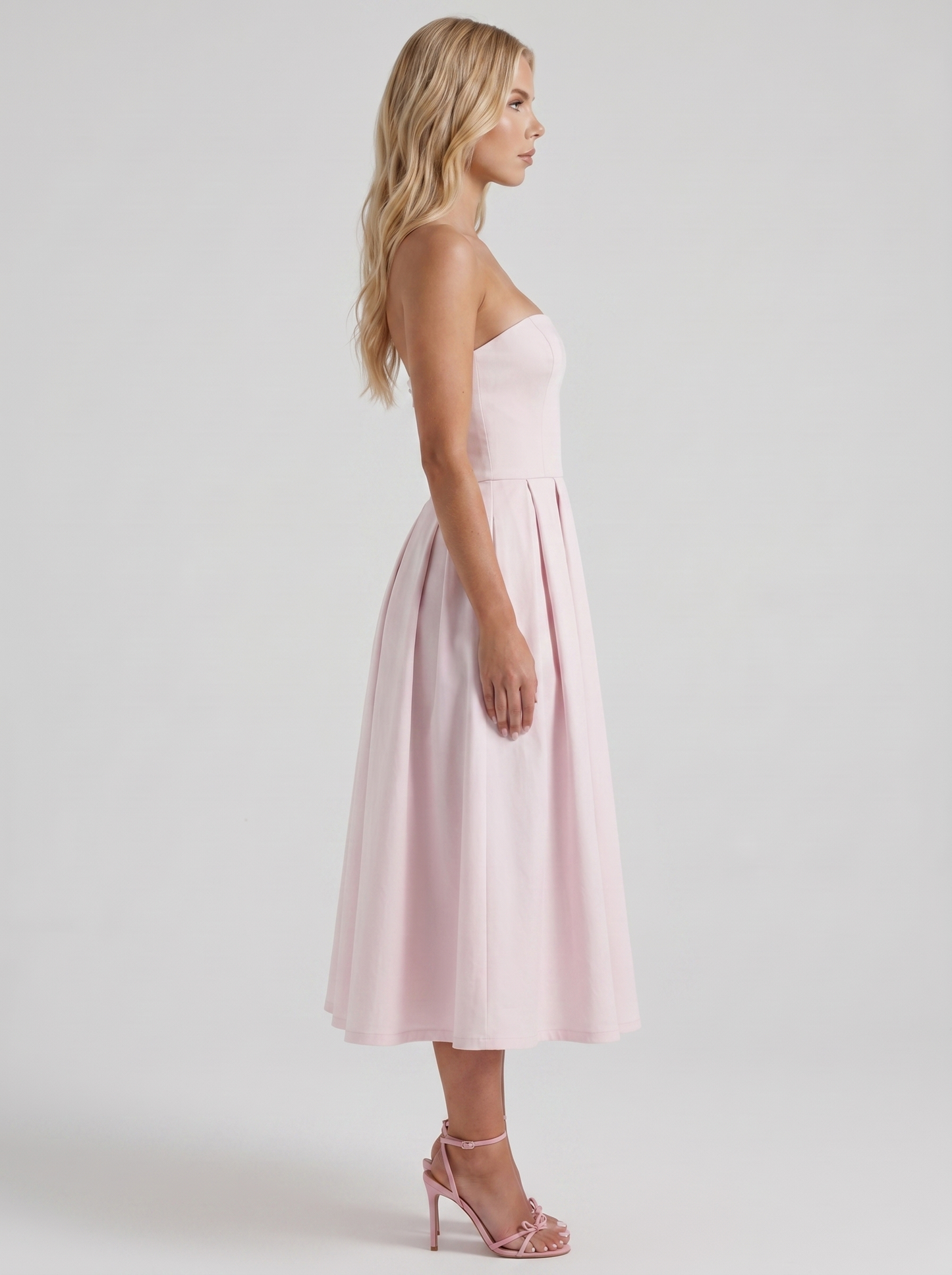 Women blush strapless pleated midi dress with fitted bodice, side profile