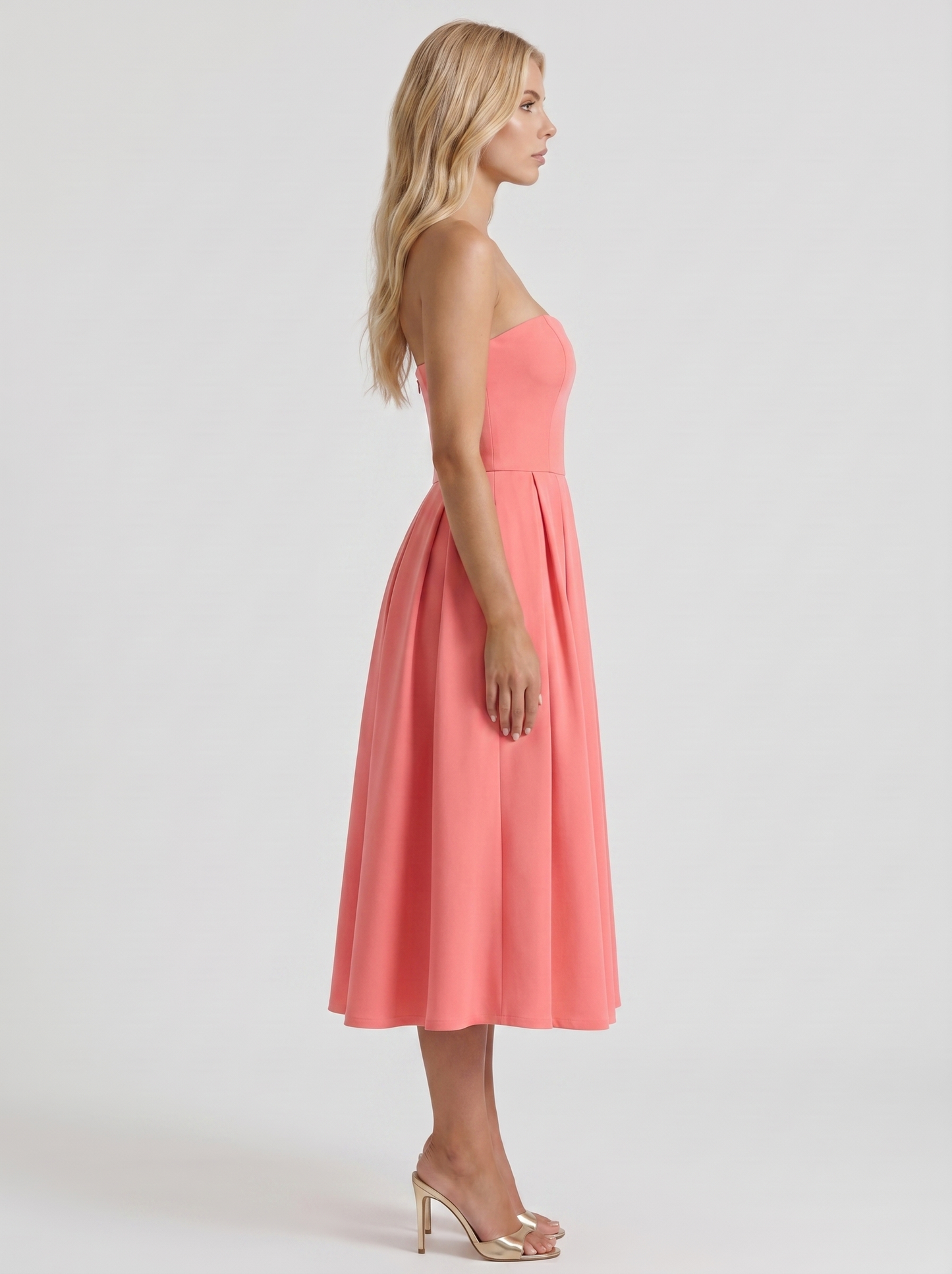 Women coral pink strapless pleated midi dress with fitted bodice, side profile