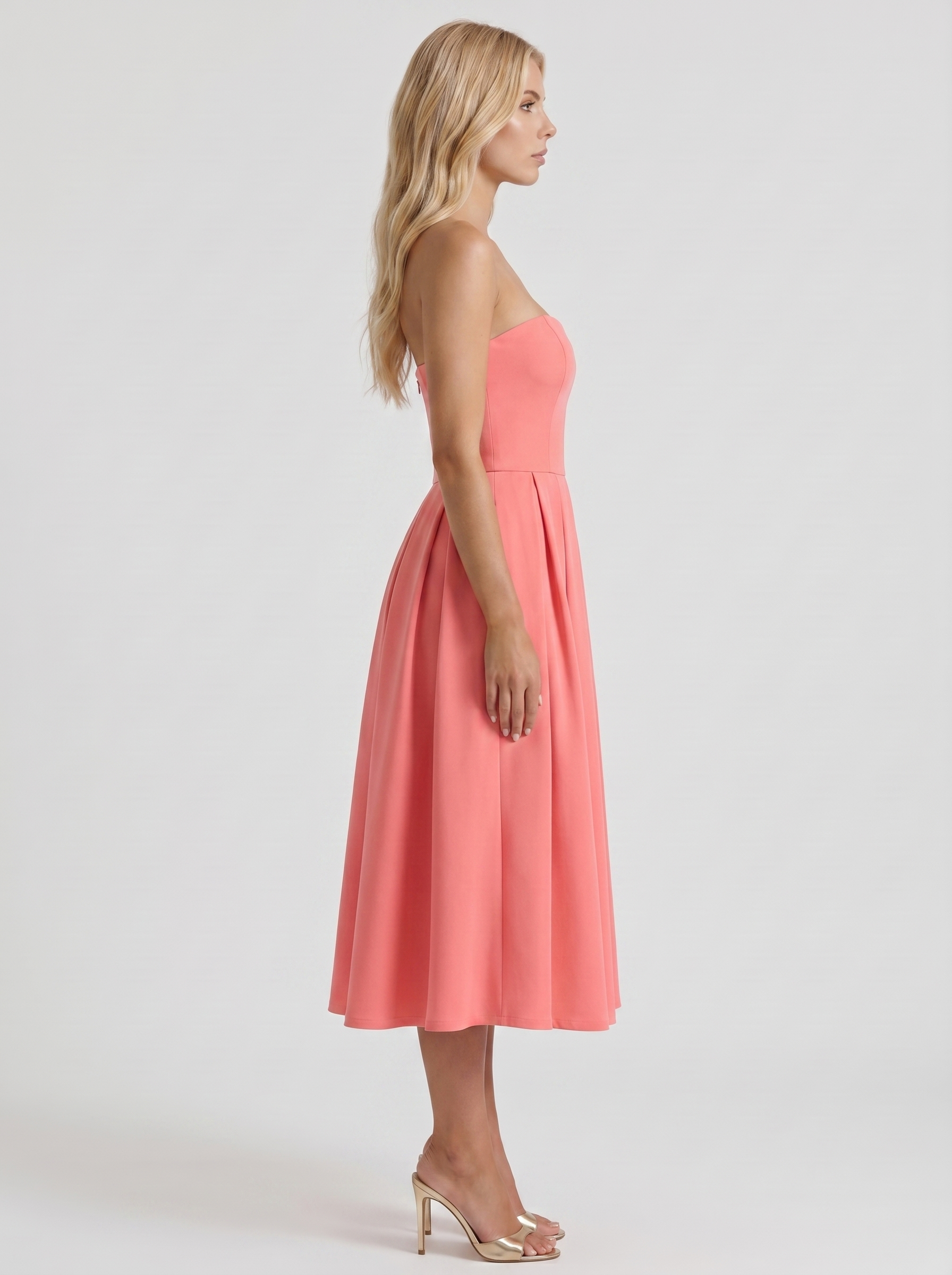 Women coral pink strapless pleated midi dress with fitted bodice, side profile