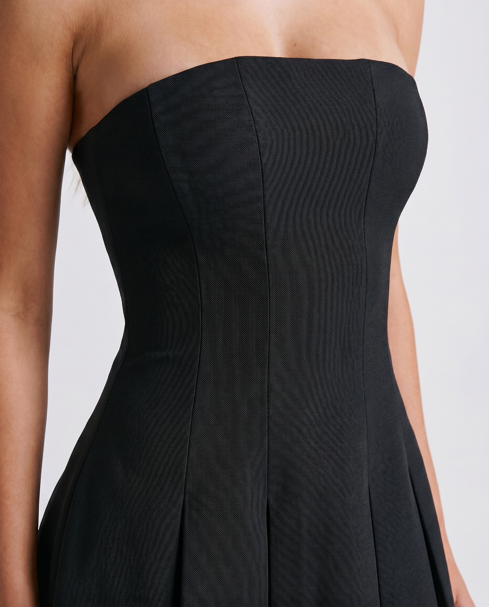 Women black strapless mini dress closeup of straight neckline, fitted bodice, and paneled seams