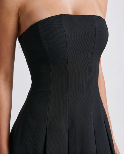 Women black strapless mini dress closeup of straight neckline, fitted bodice, and paneled seams