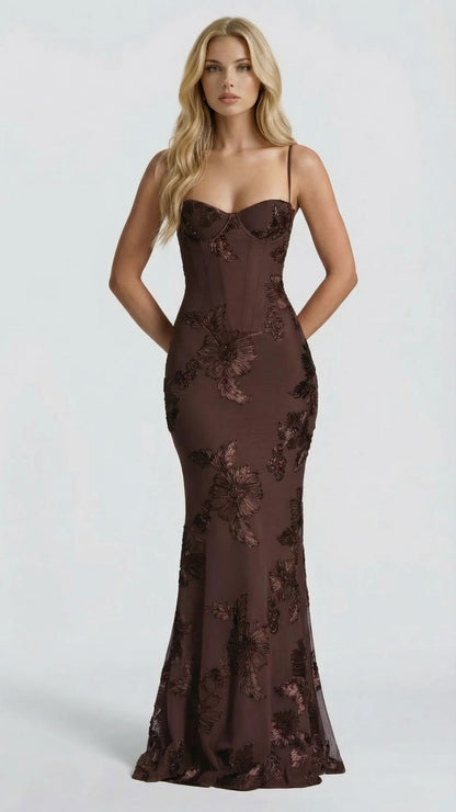 Front view of brown floral maxi dress, hands behind back, showcasing the full-length silhouette and pattern.