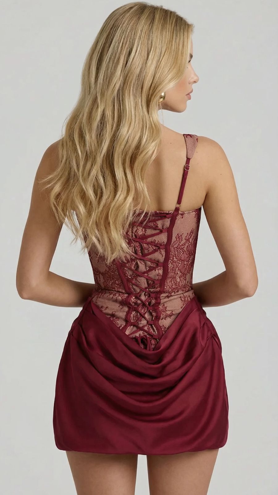 Women's burgundy lace corset mini dress, rear view revealing lace-up back closure and draped skirt.