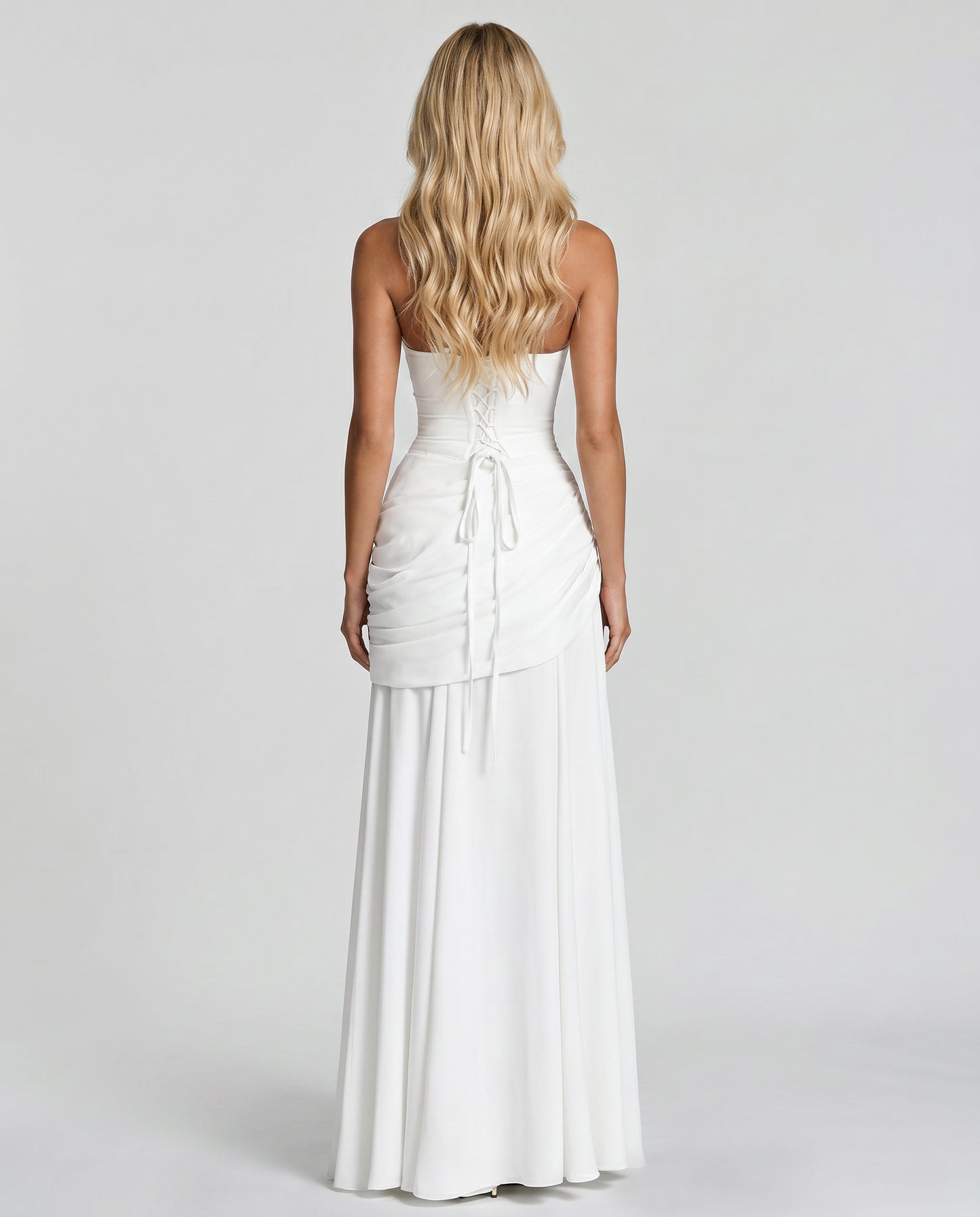 Back view of white ruched maxi dress with lace-up corset back, tie detail and flowing skirt