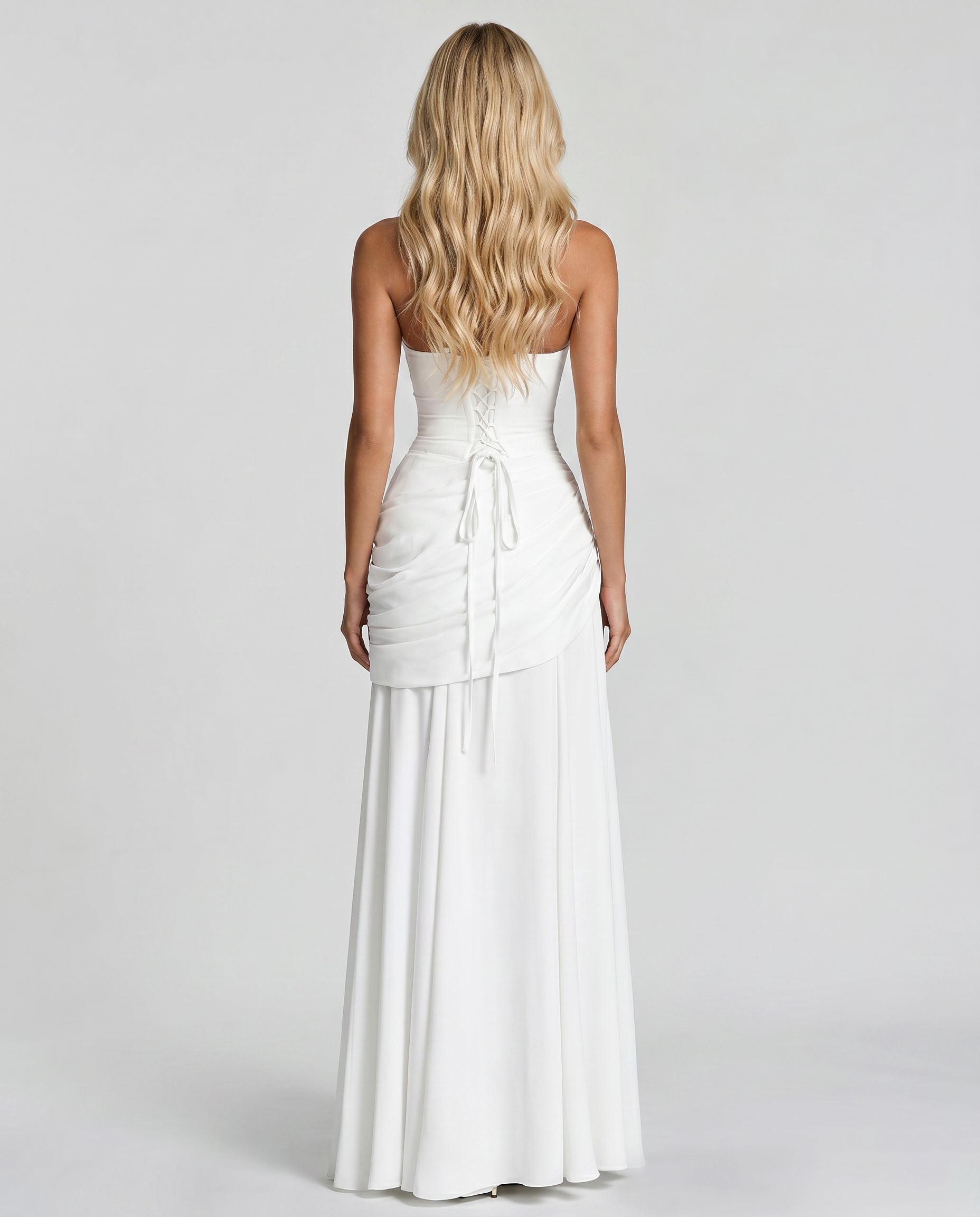 Back view of white ruched maxi dress with lace-up corset back, tie detail and flowing skirt