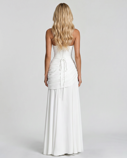 Back view of white ruched maxi dress with lace-up corset back, tie detail and flowing skirt