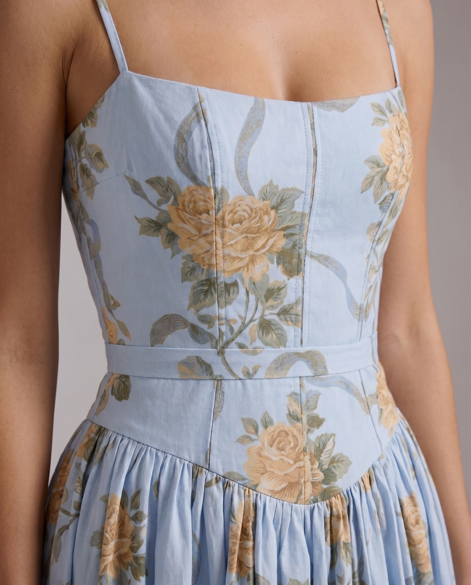 Close-up of vintage blue floral midi dress bodice with seamed panels, rose print, and waistband detail