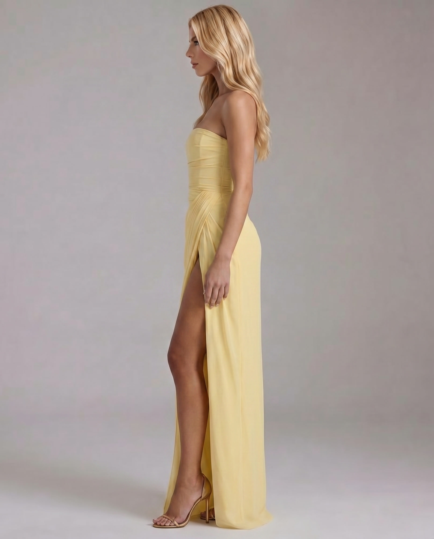 Side view yellow strapless maxi dress with ruched waist, wrap skirt, and leg slit