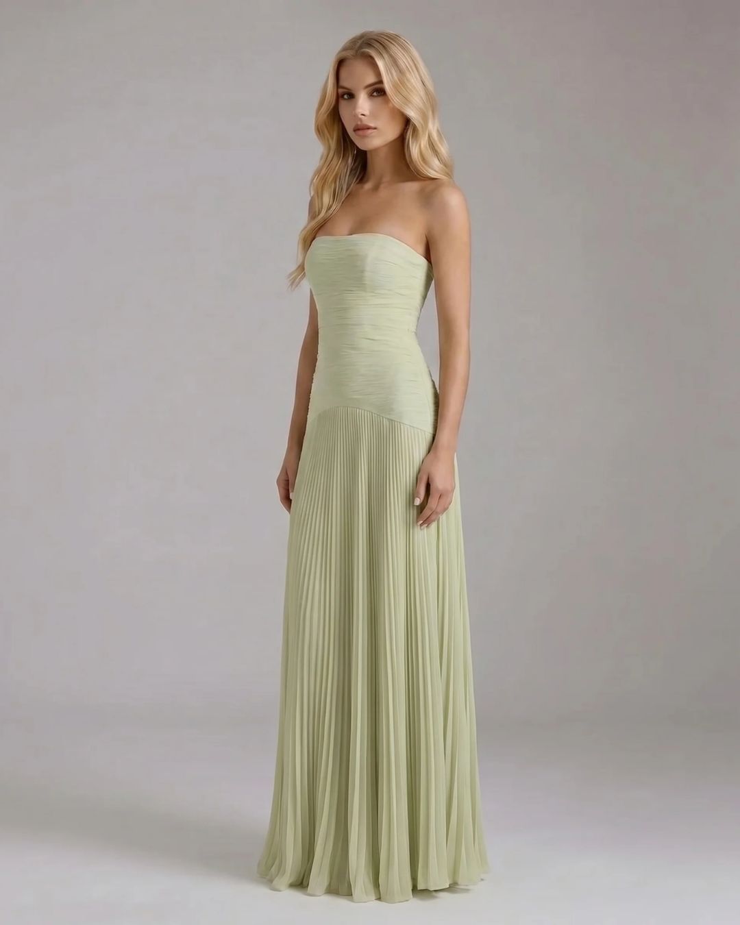 Angled view of the Kenzie Forest maxi dress, showcasing the light green fabric and the elegant pleats of the skirt.