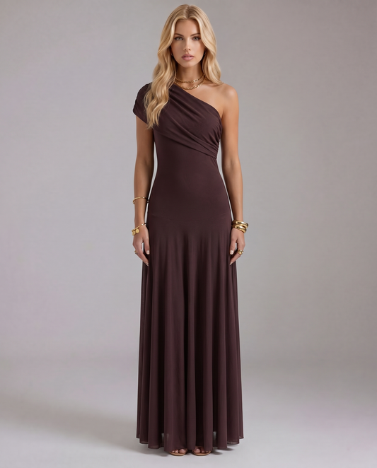 Women's brown one-shoulder maxi dress with draped bodice detail in a full front view. Model wears gold accessories.