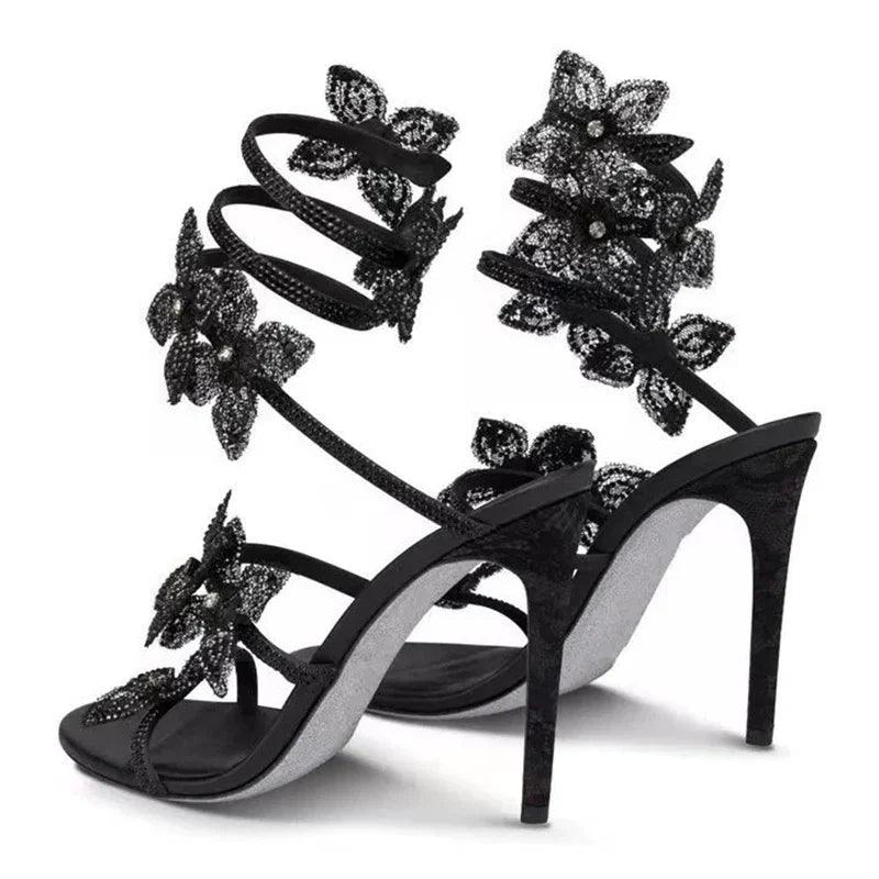 Women black heeled sandals with wrap straps and rhinestone detail