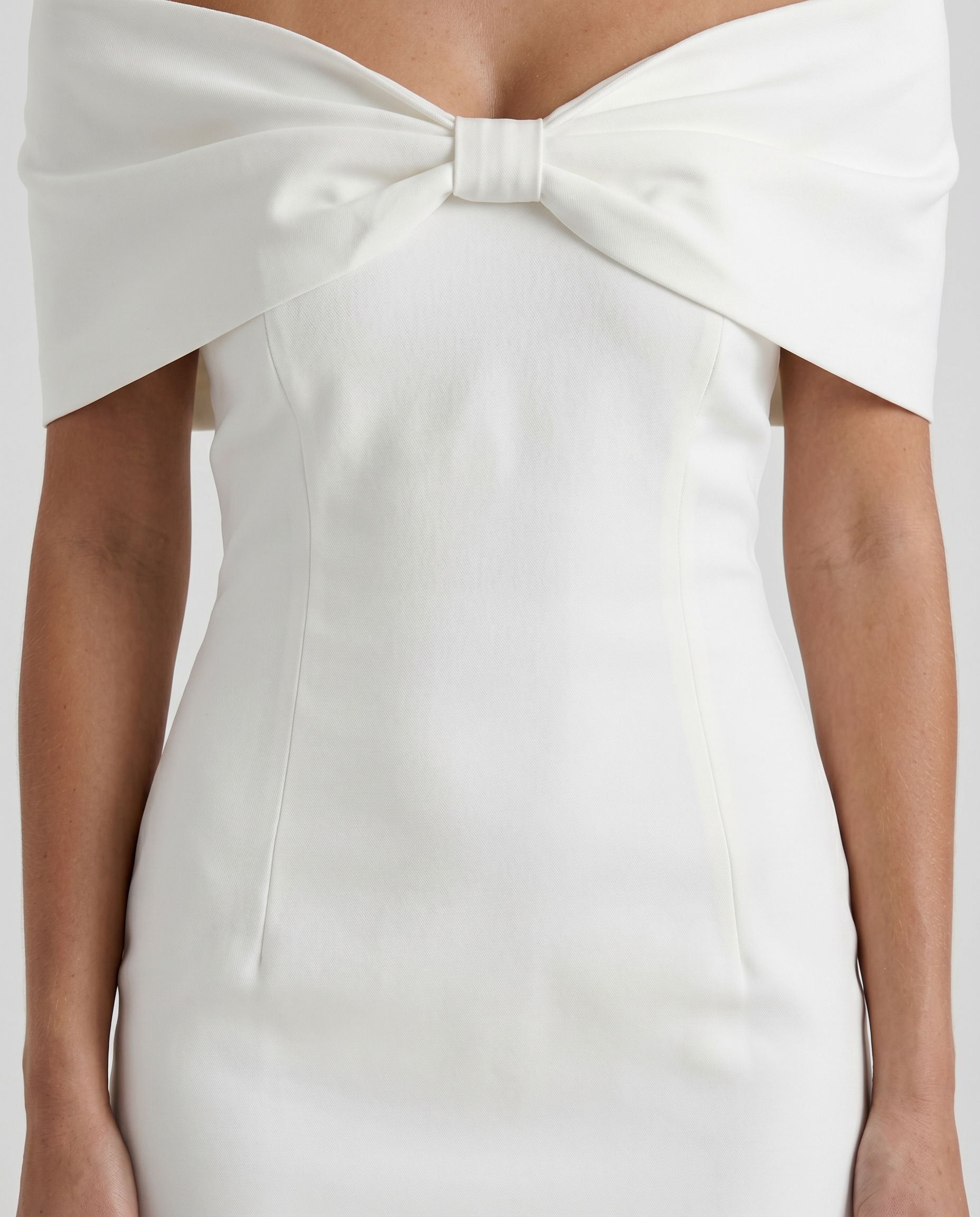 Women white mini dress closeup of off shoulder neckline, center bust bow, and cap sleeves