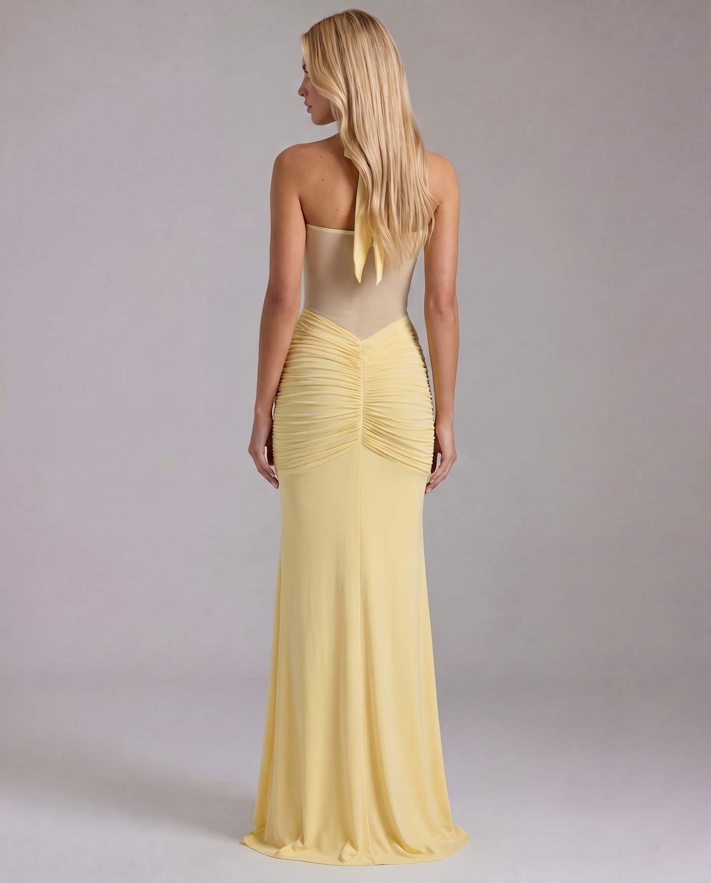Women's yellow ruched maxi dress with halter ties and sheer back panel, rear view.