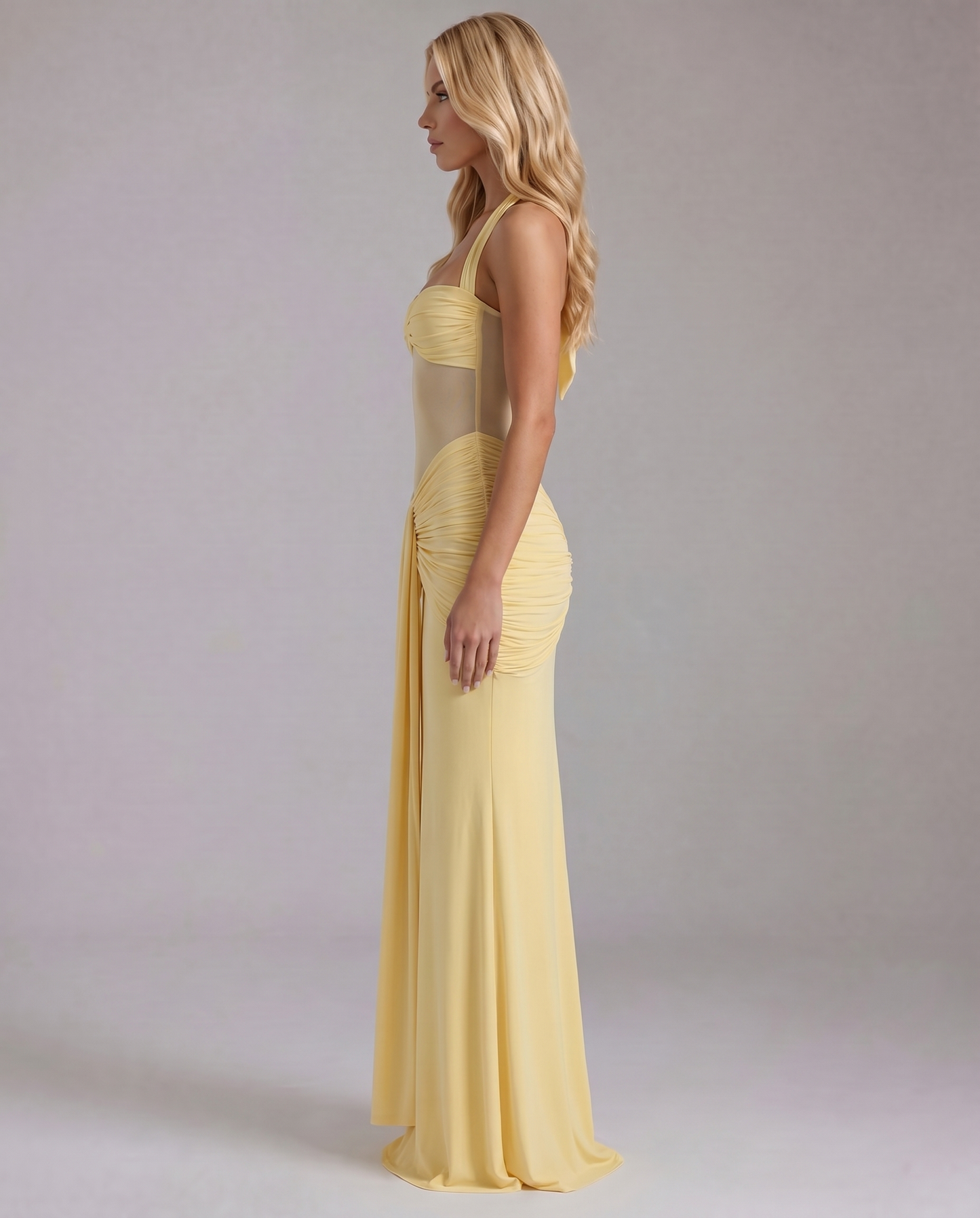 Women's yellow ruched maxi dress with twisted bust and flowing skirt, side view.